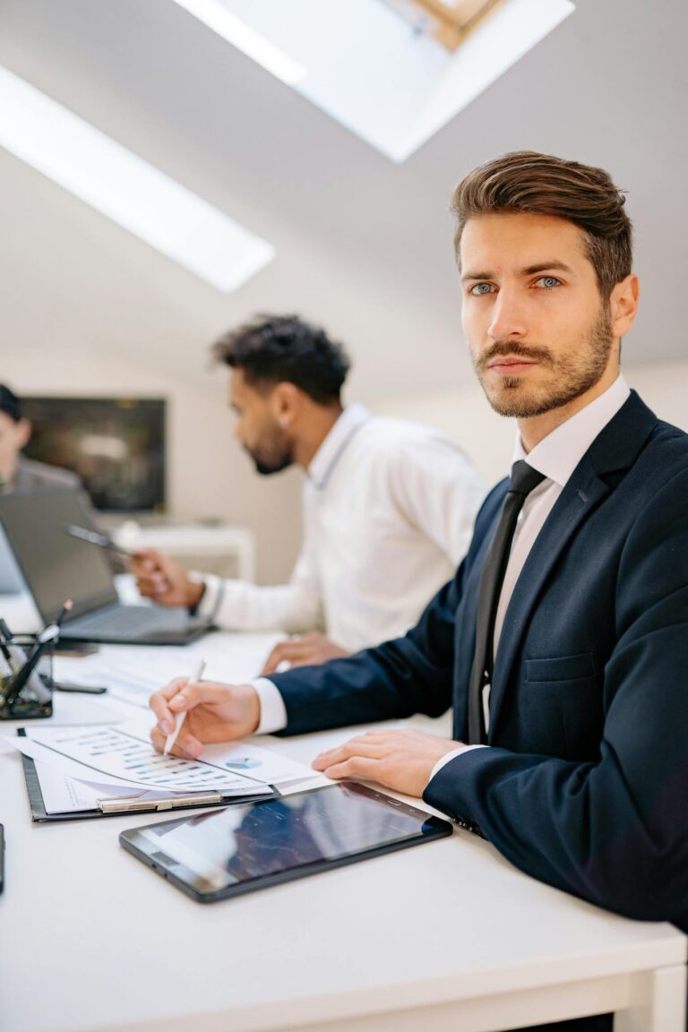 Confident businessman in formal attire attending a meeting in a modern office setting.